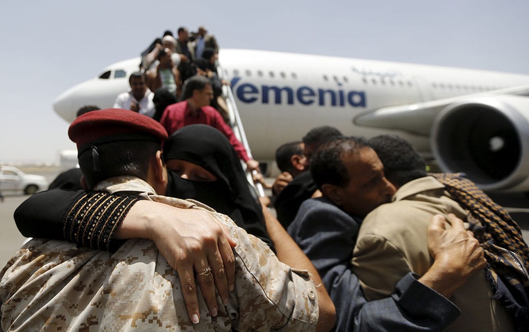 Relatives of Yemenis, who were stranded in Egypt, hug each other as they disembark from their plane after returning home, at Sanaa international airport, 20 May 20 2015. REUTERS/Khaled Abdullah